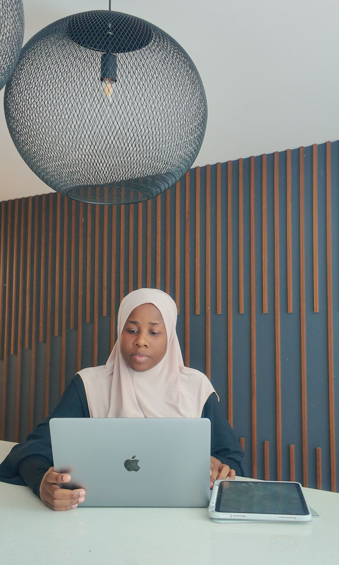 Fatimah working at her laptop, the woman behind She Shows Up